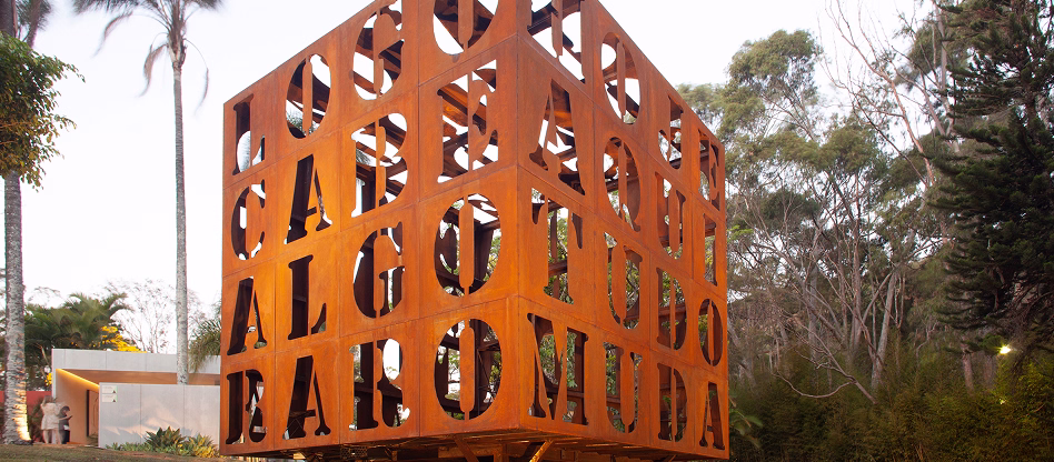 Obra Cuboesia, de João Diniz e Bel Diniz, formada por cubo em chapa de aço com textos vazados e jardim de vergalhões
