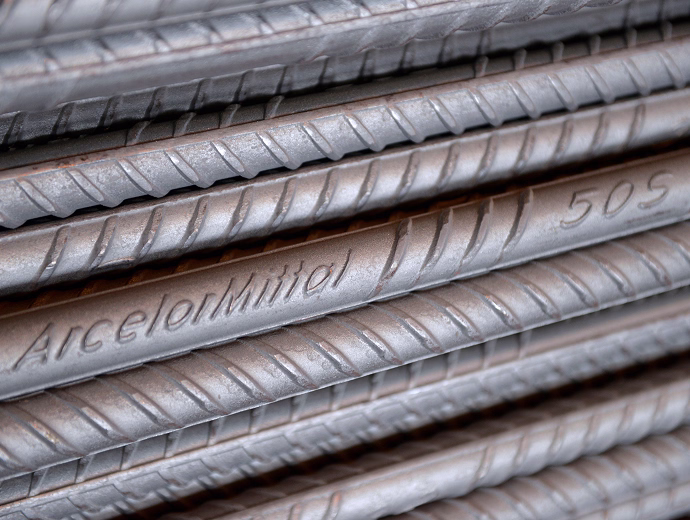 Vergalhões de aço ArcelorMittal empilhados, com destaque para a marca gravada no material