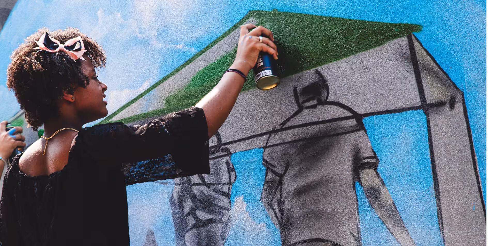 Artistas pintam mural com spray.