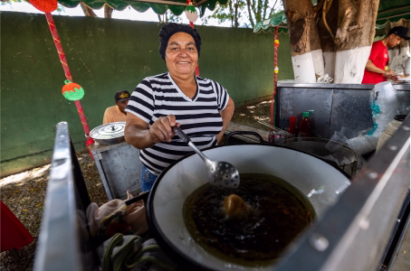 Mulher prepara alimento em evento comunitário